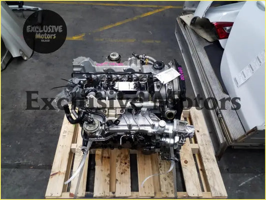 Silver metallic ford ranger weat engine block with black hoses on wooden pallet showing front side view