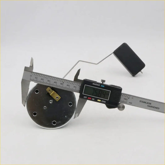 Black circular fuel gauge sending unit with six holes and gold metal piece being measured by digital caliper for toyota hilux