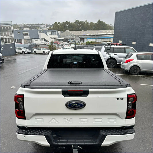 White ford ranger xlt pickup truck with black manual roller shutter tonneau cover on the back for 2022+ ranger