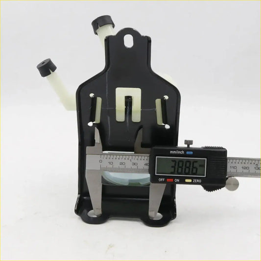 Black plastic power steering fluid reservoir with translucent white caps and caliper measuring its width for toyota hilux