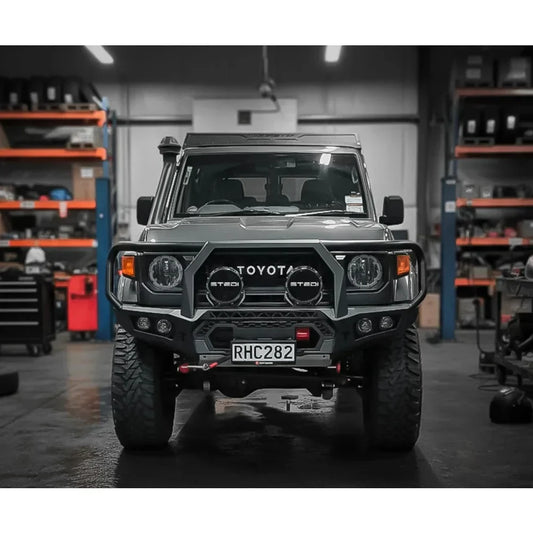 Dark gray toyota land cruiser 70 series with rugged steel rockarmor gt hoop bullbar and round headlights