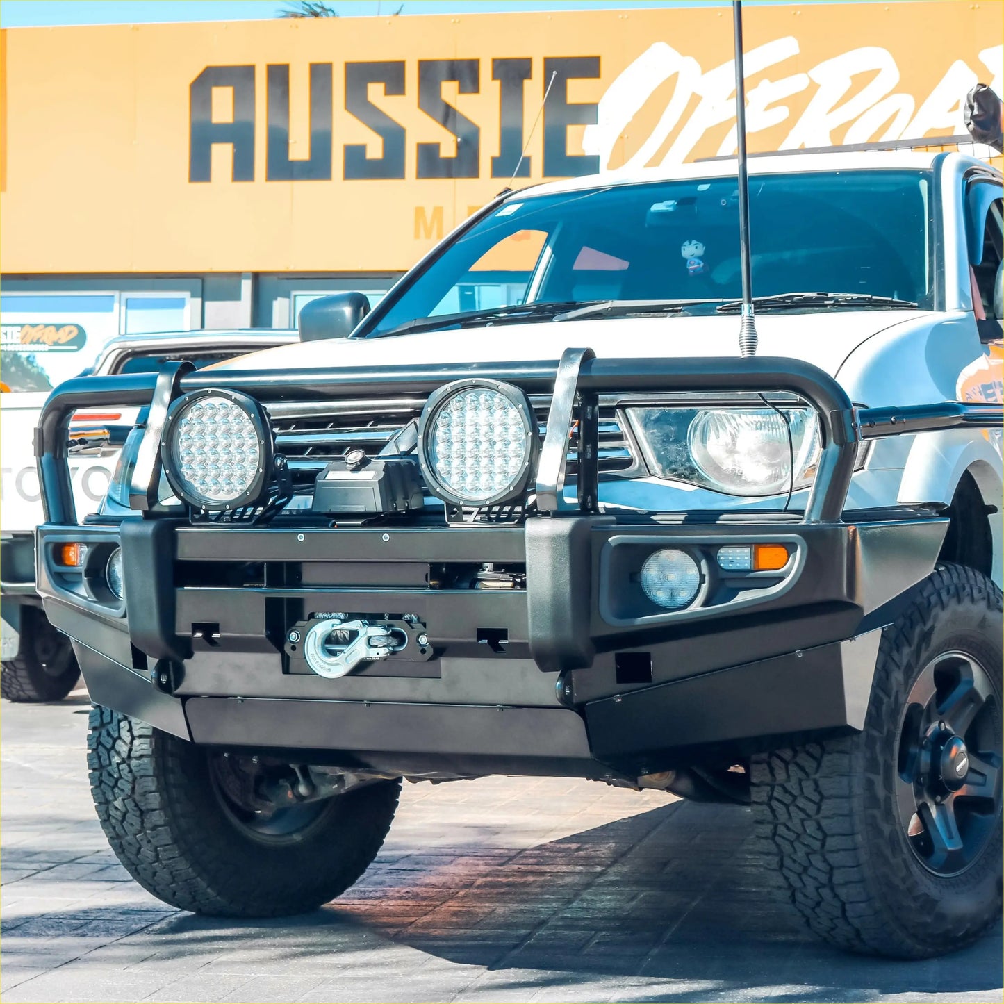 Black metal front bumper with two circular led lights and winch mount on silver mitsubishi triton challenger truck