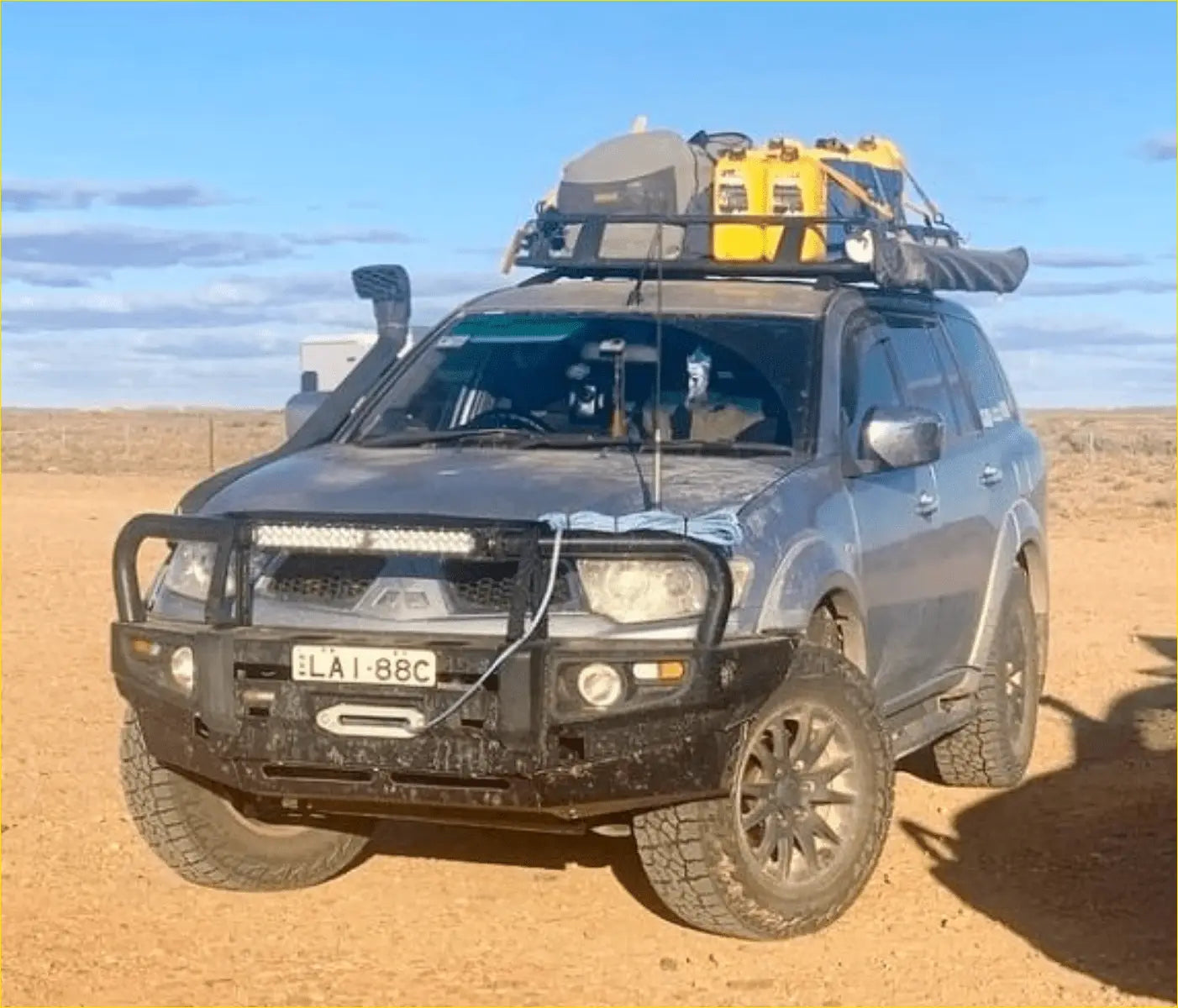 Dark gray mitsubishi pajero sport suv with black rockarmor premium steel bullbar and roof rack carrying yellow gear