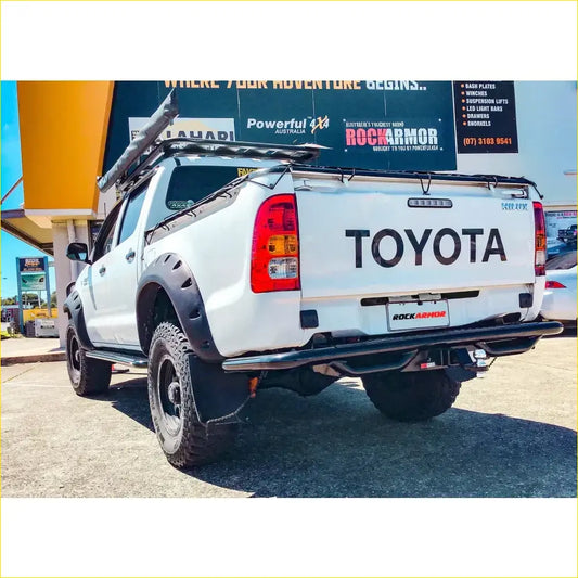 White toyota hilux with black steel rockarmor rear step tow bar and roof rack shown from the back side