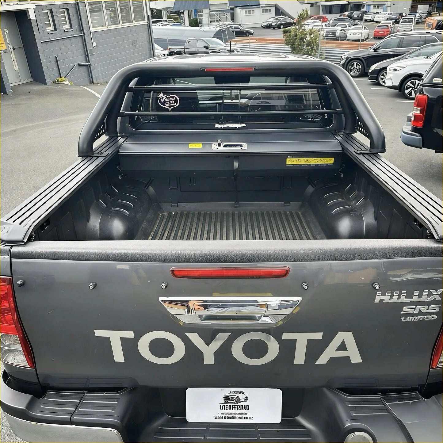 Back of black toyota hilux srs limited pickup with rugged bed liner and chrome tailgate handle featuring roll bar t10 and manual roller shutter