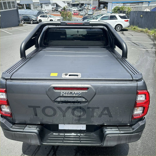 Back view of dark gray metallic toyota hilux pickup with roll bar t20 and manual roller shutter bed cover