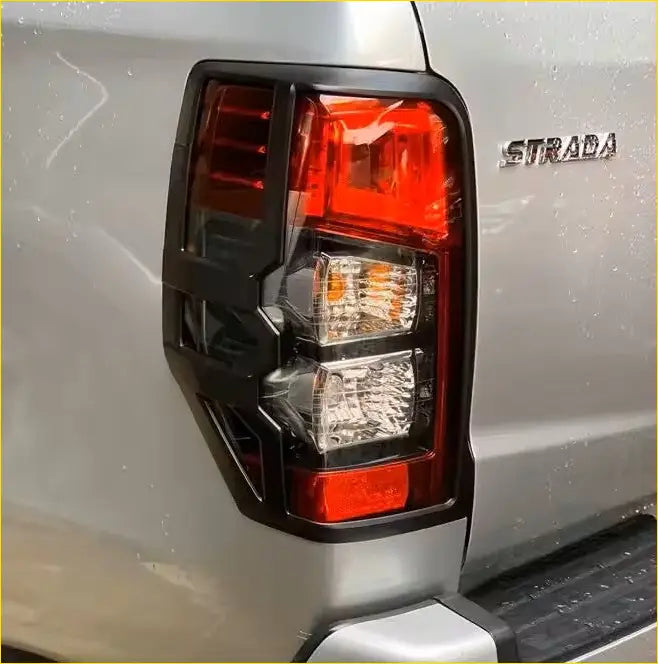 Black plastic taillight cover with red and clear lenses shown from back on silver mitsubishi triton 2019-2023 matte black