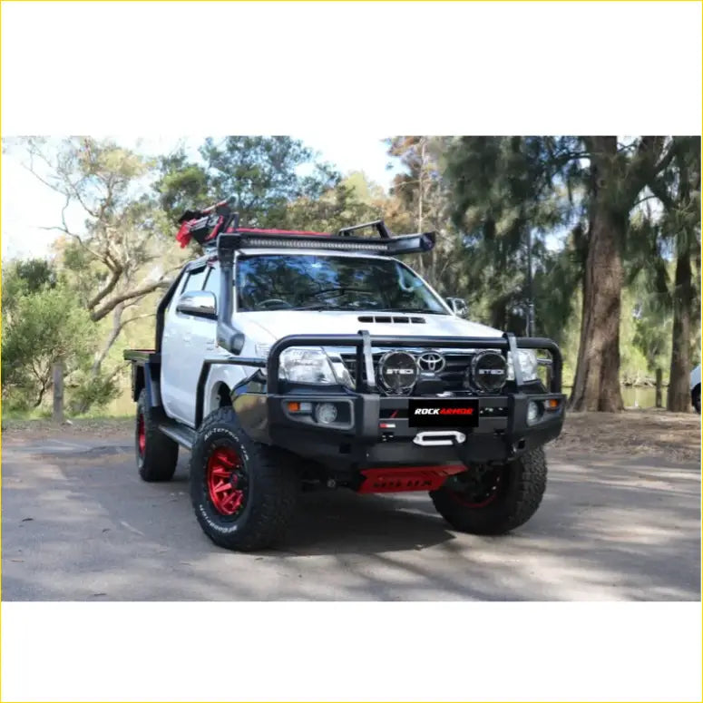 White toyota hilux pickup with black and red rockarmor aftermarket front bumper roof rack and custom wheels in nz 2026 review