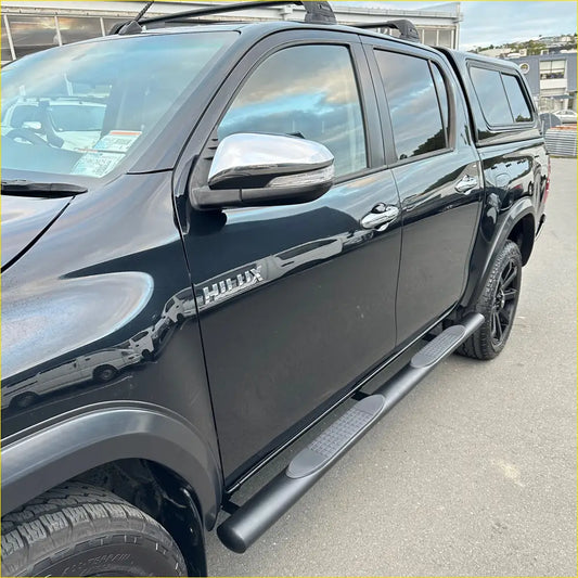 Black toyota hilux ute with chrome side mirrors and black running boards shown from the back side in NZ 2026 side steps guide