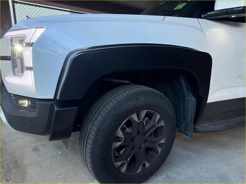 Light blue and black gmc hummer ev with rugged 2025 byd shark smooth style fender flares and dark gray alloy wheels
