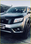 Silver nissan navara pickup truck with a black aftermarket grill nismo and rugged off-road tires