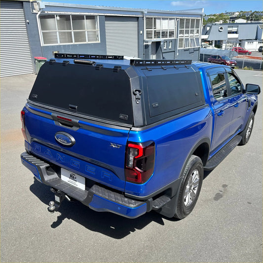 Blue ford ranger xlt pickup truck with black aluminium hardtop canopy shown from the back side