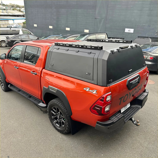 Red toyota hilux with black aluminium canopy cover and off-road tires shown from the back side for 2015-2025 sr5