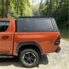 Back view of black aluminium canopy with hard-shell truck bed cover and side-mounted latches for toyota hilux 2015-2025
