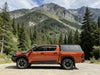 Orange toyota hilux pickup truck with black accents and aluminium canopy with rear view glass shown from the back side