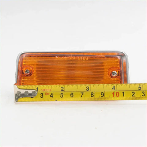 Amber side marker light for nissan datsun 620 1972-1979 with orange led, chrome bezel, and two mounting screws shown next to tape