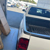 White toyota hilux pickup truck with black textured bedside rail covers 3 piece set and chrome side steps back view