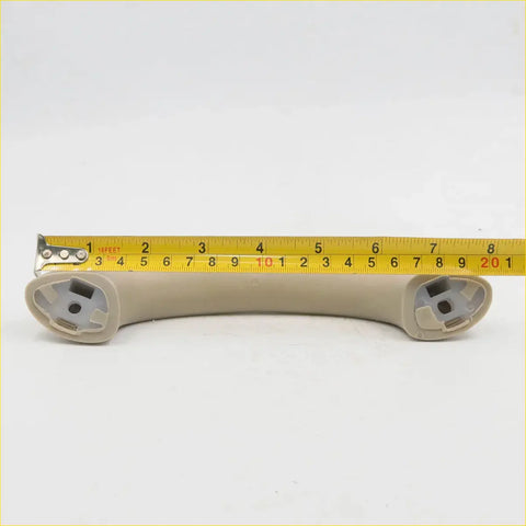 Beige plastic a-pillar grab handle with molded mounting brackets for toyota hilux sr5 2004-2016 showing back side