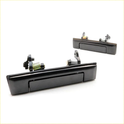 Black plastic door handle set for Toyota Hilux 1983-1997 with integrated spring mechanism and mounting hardware visible from back