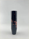 A sleek black lacquer blossom gear knob with delicate pink cherry blossoms gold accents and a small green leaf
