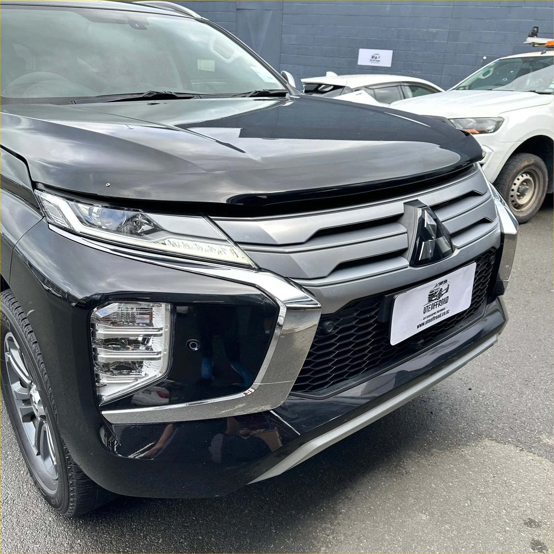 Black mitsubishi suv with a sleek glossy finish and chrome grille featuring bonnet guard protector stone guard for pajero