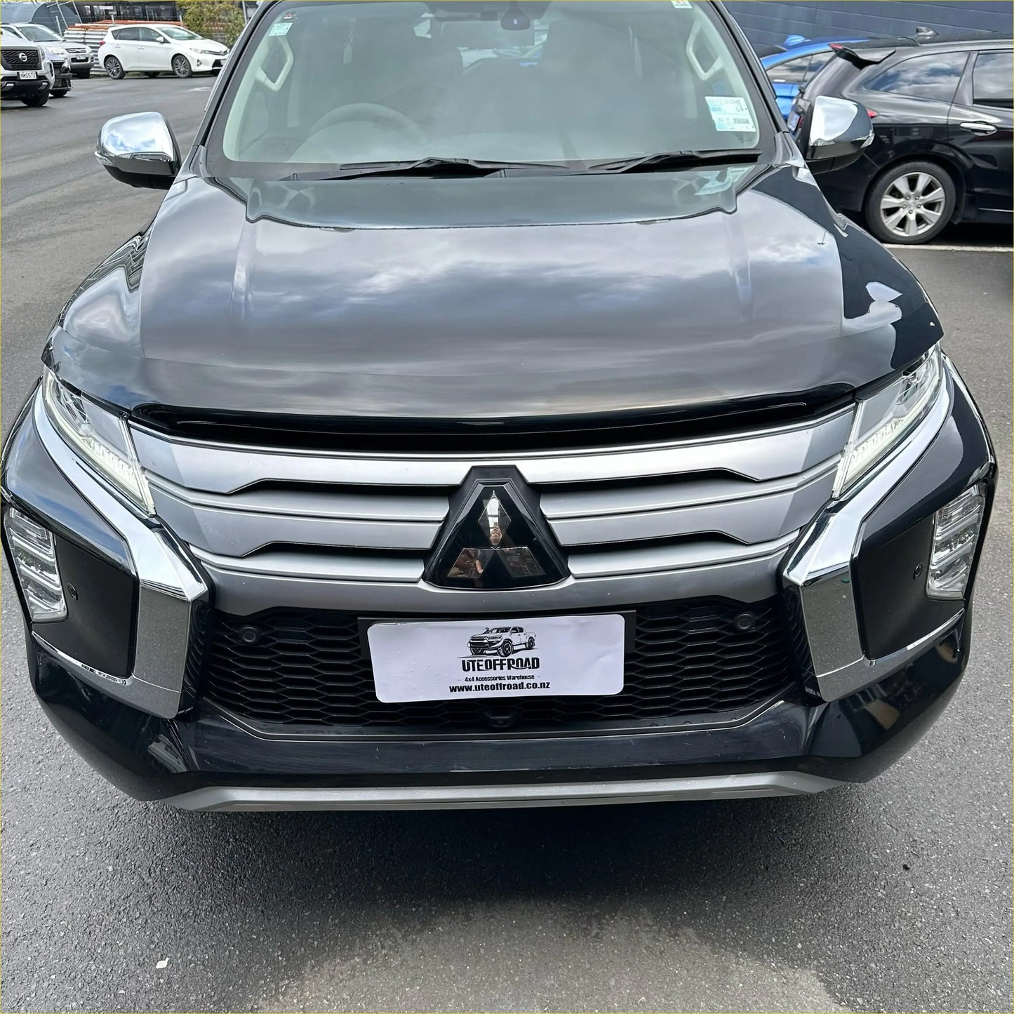Dark gray metallic mitsubishi triton with chrome grille and black bumper featuring bonnet guard protector stone guard oem