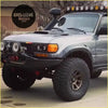 Silver toyota land cruiser lc80 with corner lights rugged off-road tires and roof-mounted light bar for tough trails