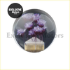 A circular transparent resin crystal flower gear shift knob with purple dried flowers on a golden textured base