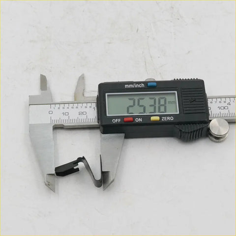 Black digital caliper measuring black metal door panel clip at 25.38 mm for toyota hilux rn10-rn40 1968-1983