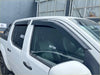 Black plastic door visors window monsoons weather shields installed on white nissan navara d40 pickup truck windows