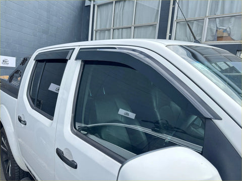 Black plastic door visors window monsoons weather shields installed on white nissan navara d40 pickup truck windows
