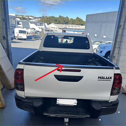 Back view of a white toyota hilux with durable textured black tailgate cover featuring chrome handle and black bed trim