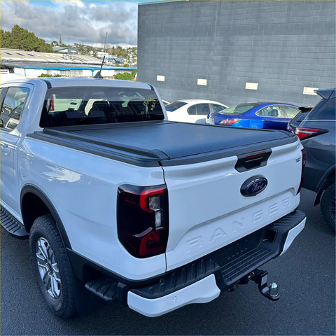 White ford ranger pickup truck with black electric roller shutter tonneau cover on the back side bed