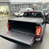 Black electric roller shutter tonneau cover on the back side of a mitsubishi triton 2024+ pickup truck bed