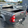 Dark gray toyota hilux with black electric roller shutter tonneau cover on the back side bed