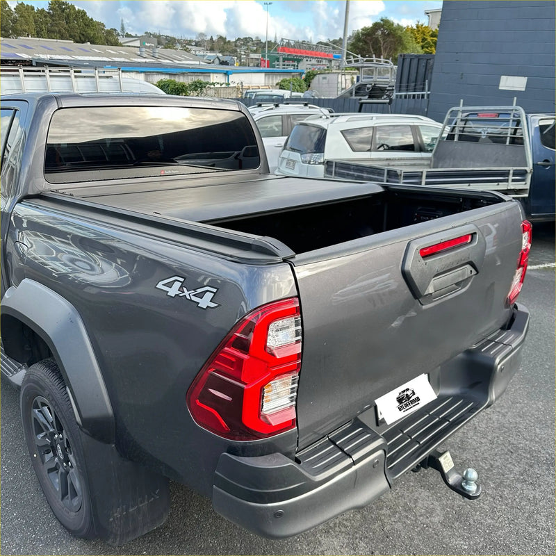 Dark gray toyota hilux with black electric roller shutter tonneau cover on the back side bed