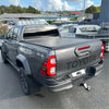 Dark gray toyota hilux with black electric roller shutter tonneau cover and 4x4 badging shown from the back side