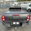 Back view of dark gray toyota hilux with black electric roller shutter tonneau cover over the truck bed