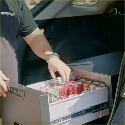 Silver-framed compact car fridge with digital temp display and sliding drawer filled with soda for ute and offroad use
