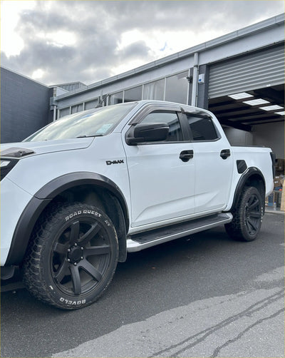 White d-max pickup truck showing rear with matte black 4-inch fender flares black wheels and side steps