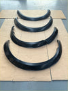 Black glossy 4 inch fender flares for Nissan Navara 2021 plus arranged on cardboard in descending size