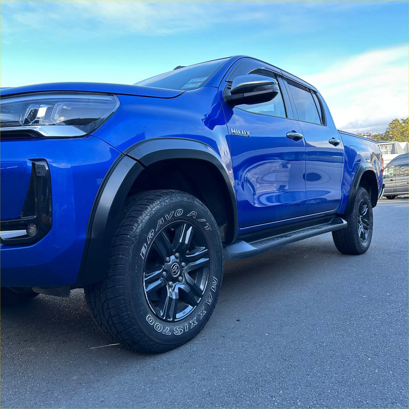 Vibrant blue toyota hilux with matte black 4-inch fender flares and black alloy wheels for rugged off-road use
