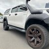 White toyota hilux 2015-2017 with lychee texture bolt style fender flares and black aftermarket body kits visible from back side