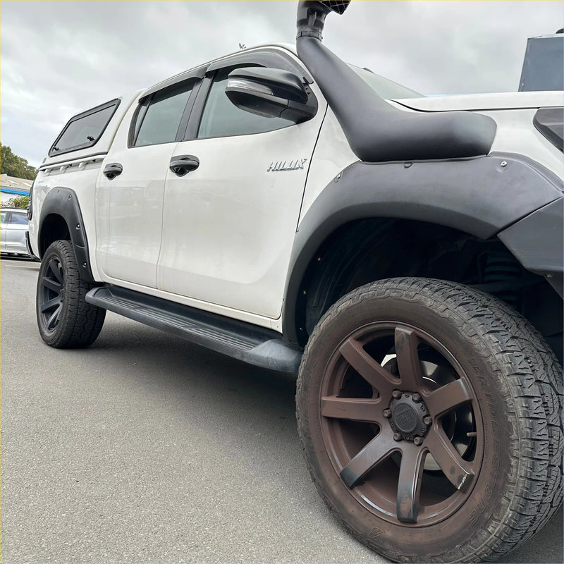 White toyota hilux 2015-2017 with lychee texture bolt style fender flares and black aftermarket body kits visible from back side