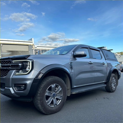 Gray metallic ford ranger with matte black sport smooth style fender flares and black roof rack off-road tires