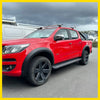 Vibrant red chevrolet colorado with matte black smooth style fender flares and rugged off-road tires on black alloy wheels