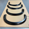 Black glossy smooth style fender flares for isuzu d-max 2016-2020 arranged in descending size on cardboard