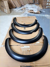 Black matte fender flare extensions for nissan navara d40 2005-2015 arranged on cardboard in smooth style