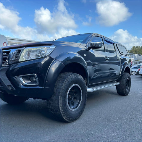 Black nissan navara np300 2015-2020 with bolt style fender flares and rugged off-road tires in a glossy finish