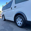 White toyota hiace van with matte black sport style fender flares and silver alloy wheels from 2005 to 2019 model